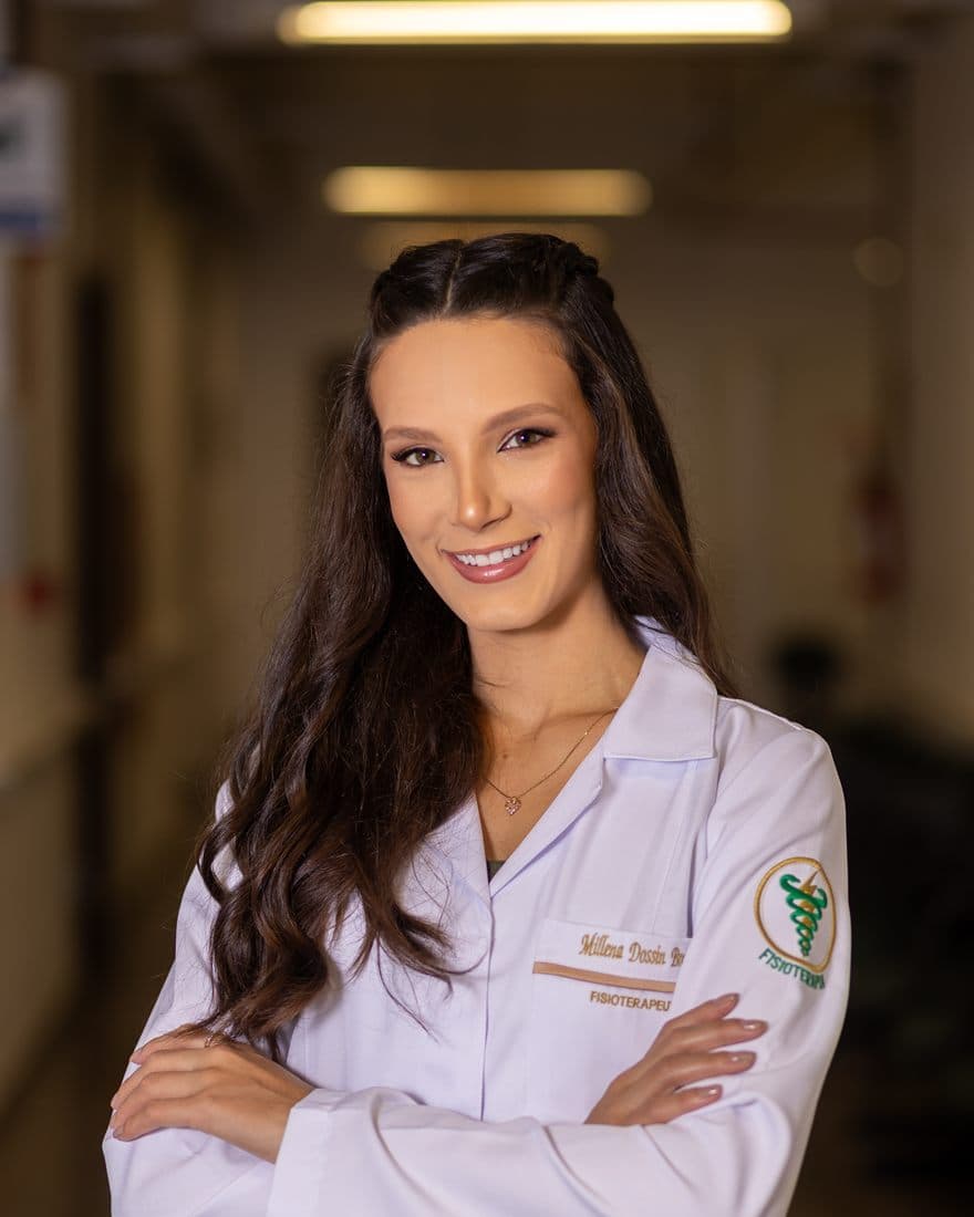 Millena Dossin Broilo, fisioterapeuta, de jaleco branco e braços cruzados
